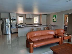 a living room with a leather couch and a kitchen at Haven Retreat in Pacific Harbour