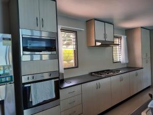 a kitchen with white cabinets and a stove top oven at Haven Retreat in Pacific Harbour +3 photos