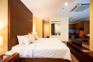 a bedroom with a white bed and a television at Elite Suites Patong in Patong Beach