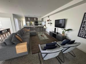 a living room with a couch and chairs and a kitchen at Amaroo by the beach in Queenscliff
