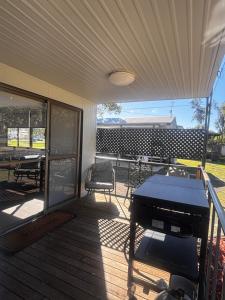 a screened porch with a piano and a table and chairs at Pioneer Caravan Park in Dalby