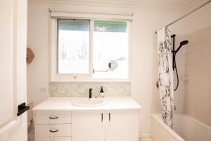 a white bathroom with a sink and a window at Aurora in Queenscliff +19 photos