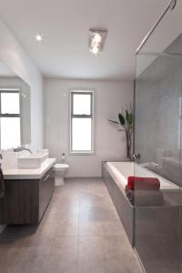 a bathroom with a tub and a toilet and a sink at Amaroo by the beach in Queenscliff +8 photos