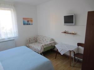a bedroom with a bed and a chair and a tv at Guesthouse Leasol in Lucija