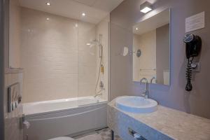 a bathroom with a tub and a sink and a bath tub at Opera Hotel in Riga