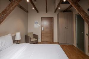 a bedroom with a white bed and a chair at Opera Hotel in Riga