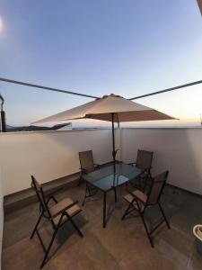 a table with chairs and an umbrella on a balcony at Casa Juanito Rute in Rute