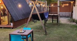 a table and chairs next to a house with a swing at Chalé Selá - Recanto 23 - Espaço Inteiro - Entre Angra e Paraty in Angra dos Reis