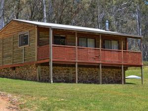 a large wooden house on a stone wall at Cabin 5 - Snowy Accommodation in Adaminaby