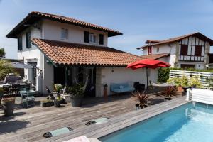a house with a wooden deck and a swimming pool at Chambre d'hôtes Ganttipienea in Ahetze