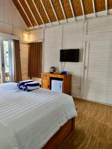 a bedroom with a large bed and a flat screen tv at Jalana Palm Villa in Tabanan