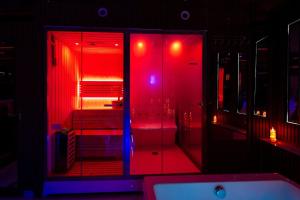 a bathroom with red lights and a shower with a sink at Le miroir secret in Gien