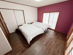 a bedroom with two beds and a purple wall at アザミヴィラ青島 in Miyazaki