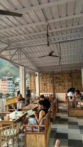 a group of people sitting at tables in a restaurant at GreenDay Escapes Rishikesh in Rishīkesh