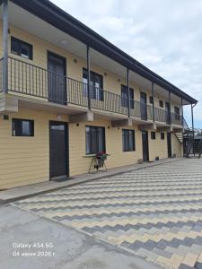 a large yellow building with a patio in front of it at NovaMotel in Karakol