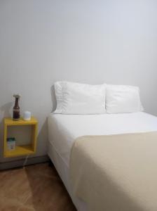 a white bed with a yellow night stand next to it at Casa com piscina em Aldeia Velha in Quartéis