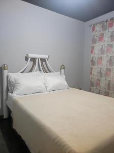 a bed with white sheets and pillows in a room at Casa com piscina em Aldeia Velha in Quartéis