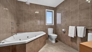 a bathroom with a tub and a toilet and a sink at Alpenglow in Dinner Plain +21 photos