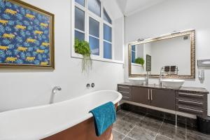 a bathroom with a tub and two sinks and a large mirror at Chapel On Moray - Apartment in Dunedin +27 photos