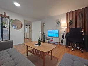 a living room with a couch and a table and a television at JIRVISTA-Homes, voll ausgestattete Wohnung im EG, kontaktloser Zutritt in Burghausen