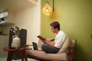 a man sitting on a couch reading a book at Nagomi Studio Nyanyi in Cemagi
