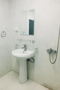 a white bathroom with a sink and a mirror at Lavanga Express in Hikkaduwa