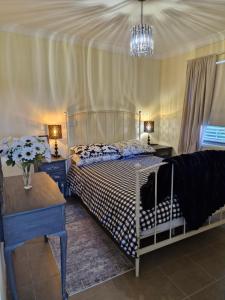 a bedroom with a bed and two tables and a chandelier at Vibrant & Vintage B & B in Greenmount