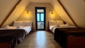 a attic room with two beds and a doorway at OSTROG Aparthotel KOLIBA-VLASTNIŠTVO MANASTIRA OSTROG in Nikšić