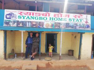 two adults and a child standing in front of a house at Syangbo Homestay in Nagarkot