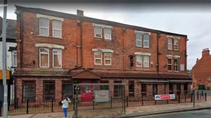 a woman standing in front of a brick building at Amber Serviced Rooms - Free parking Self Check-In with access to shared kitchen in Hull