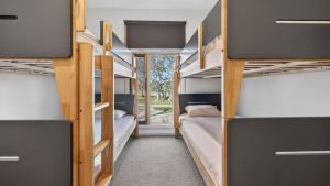 ein Zimmer mit vier Etagenbetten und einem Fenster in der Unterkunft Alpine Walkabout in Dinner Plain