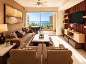 a living room with a couch and a tv at Luxury Beachfront Condo at Del Canto Residences - Amazing Views! in Nuevo Vallarta