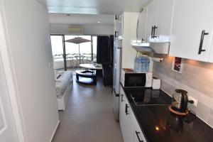 a kitchen with white cabinets and a living room at VIP CONDO RAYONG 343 in Rayong