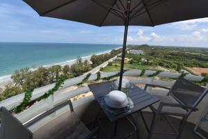a balcony with a table and an umbrella and the ocean at VIP CONDO RAYONG 343 in Rayong