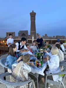 a group of people sitting around a table eating food at Golden Minaret with Terrace in Bukhara