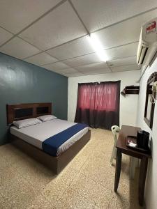 a bedroom with a bed and a table and a window at planet hotel mersing in Mersing