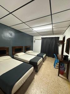 a hotel room with two beds and a desk and a room with two beds at planet hotel mersing in Mersing