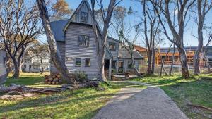 an old house in the middle of a yard with trees at Coho in Dinner Plain