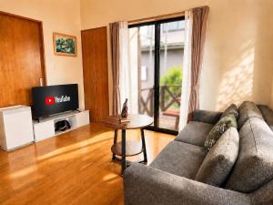 a living room with a couch and a television at Hamabun テラスでBBQ 湖まで徒歩5分 無料駐車場3台 in Takashima