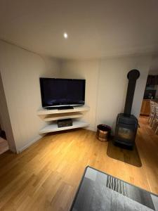 ein Wohnzimmer mit Flachbildfernseher und Holzofen in der Unterkunft Ravnklo in Sørkjosen