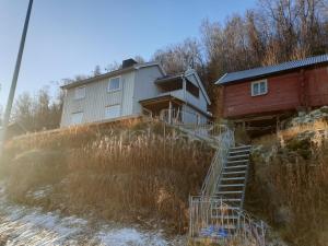 ein Haus, das auf einem Hügel neben einem Haus steht in der Unterkunft Ravnklo in Sørkjosen