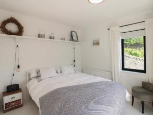 a white bedroom with a bed and a window at West Island in Kingsbridge