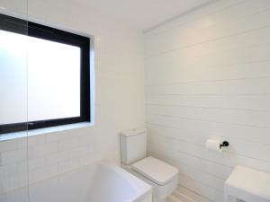 a white bathroom with a toilet and a window at West Island in Kingsbridge