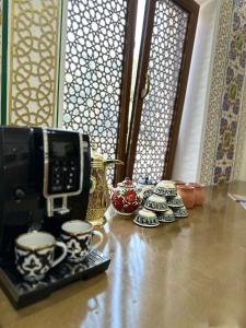 a counter with cups and a coffee maker on a table at Zarhal boutique Premium in Bukhara