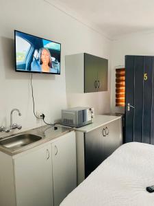 a room with a kitchen with a tv on the wall at Linies guest house northmead in Benoni