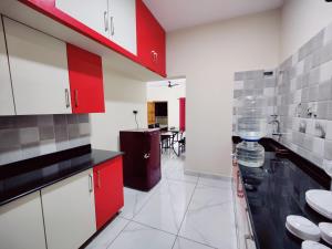 a kitchen with red and white cabinets and a sink at Mysore Studio Rooms in Mysore