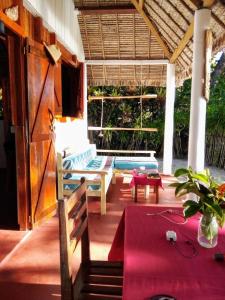 a porch with benches and a table on a house at Bungalow Ambanivolo in Sainte Marie
