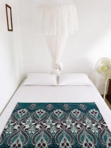 a bed with a blue and white blanket on it at Jungle life guesthouse Trekking & Transport Book with us in Bukit Lawang