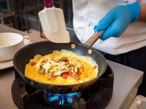 a person cooking food in a pan on a stove at Windsor Hotel Taichung in Taichung
