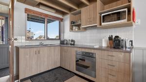a kitchen with wooden cabinets and a microwave at Freedom in Dinner Plain +8 photos